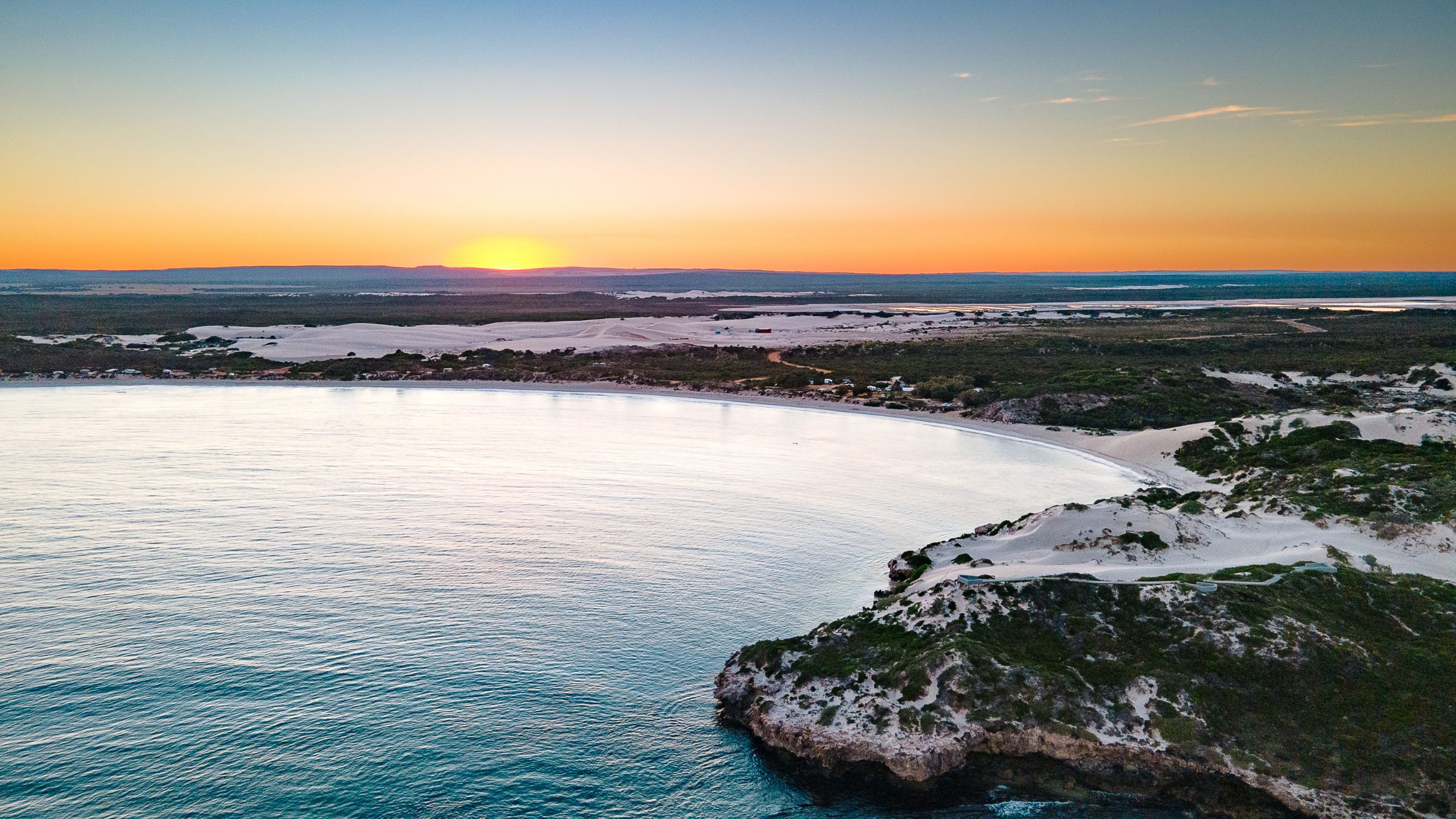 Early morning sunrise illuminating the shoreline and sand dunes of Sandy Cape, Western Australia.