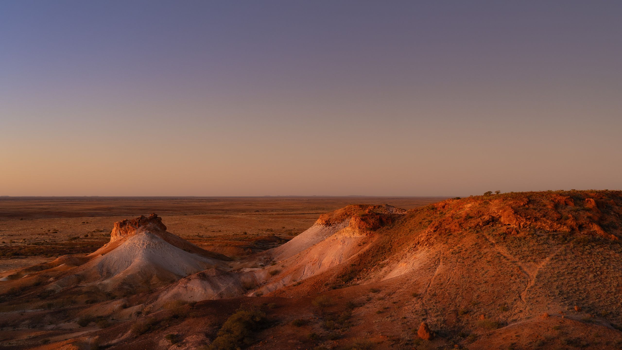 Vivid desert landscape of Kanku Breakaways illuminated by the setting sun, highlighting layered cliffs and open plains.