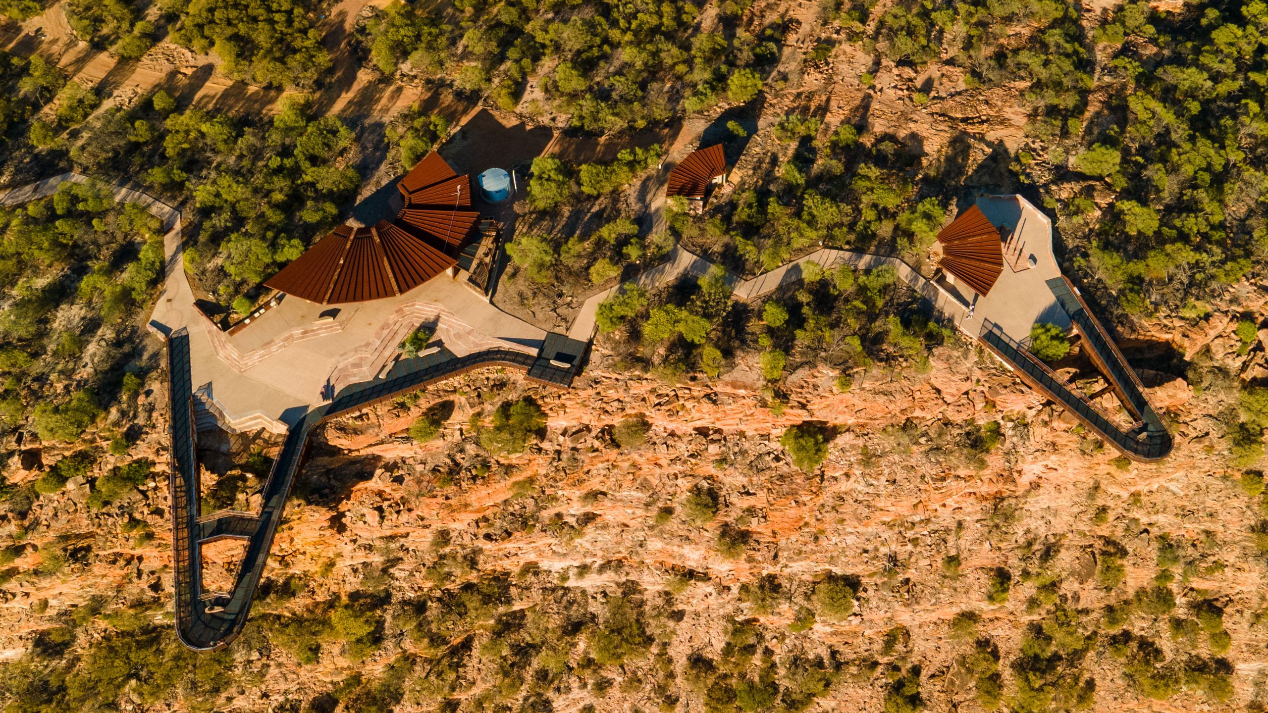 Aerial drone view of Kalbarri Skywalk in Kalbarri National Park, Western Australia, featuring cantilevered platforms extending over the Murchison River Gorge with dramatic red cliffs and scenic outback landscape