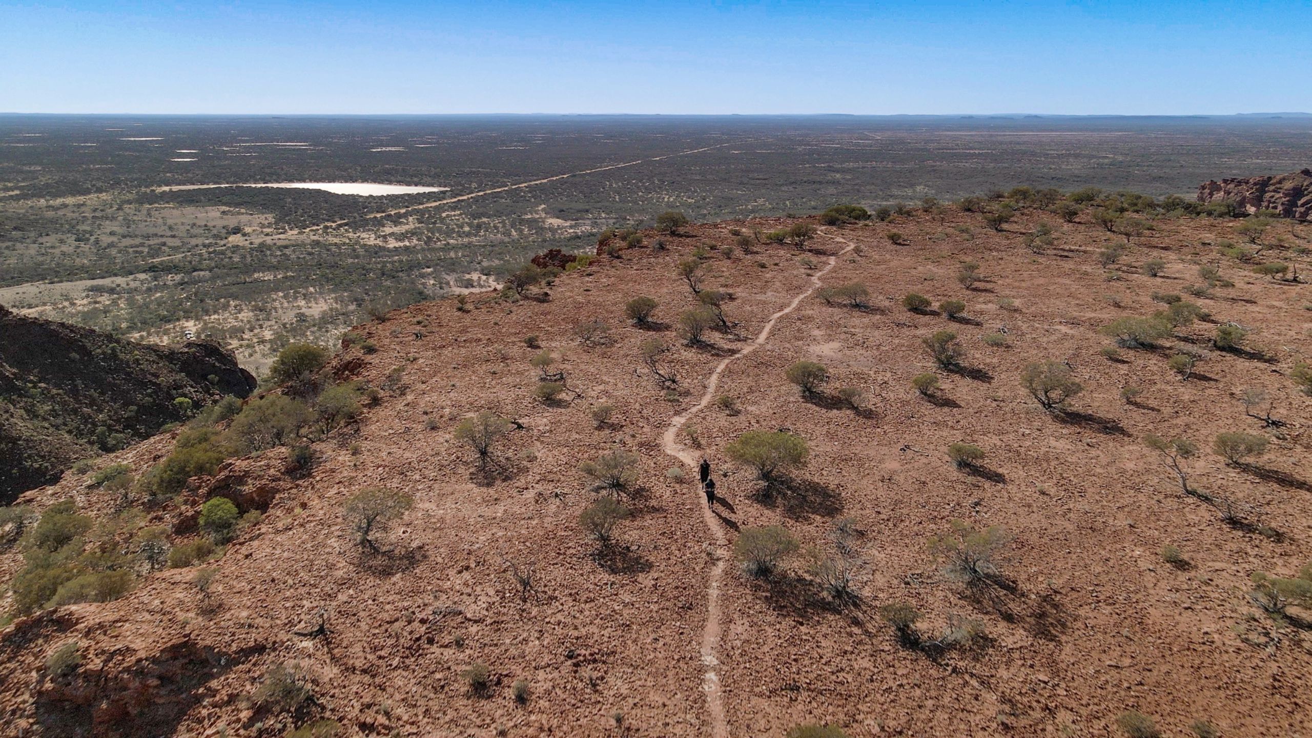 Two hikers on the Kennedy Range Escarpment Trail plateau, with sweeping views of the Western Australian outback plains in Kennedy Range National Park.
