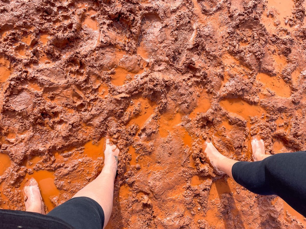 Bare feet sinking into the cracked, muddy surface of Lake Ballard’s salt flats in Western Australia