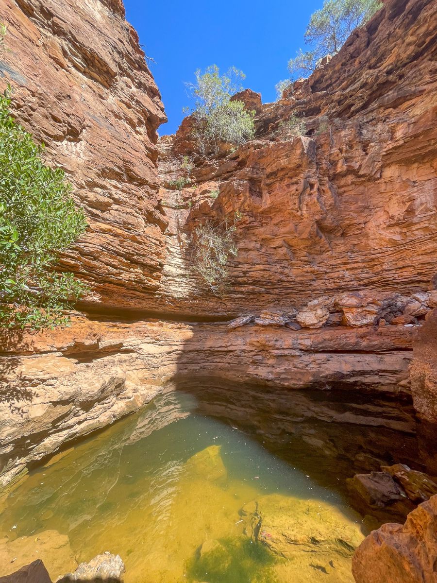 Waterhole at the end of the Drapers Gorge hiking trail, Kennedy Range National Park, Western Australia, surrounded by red rock walls and a seasonal waterfall now dry.