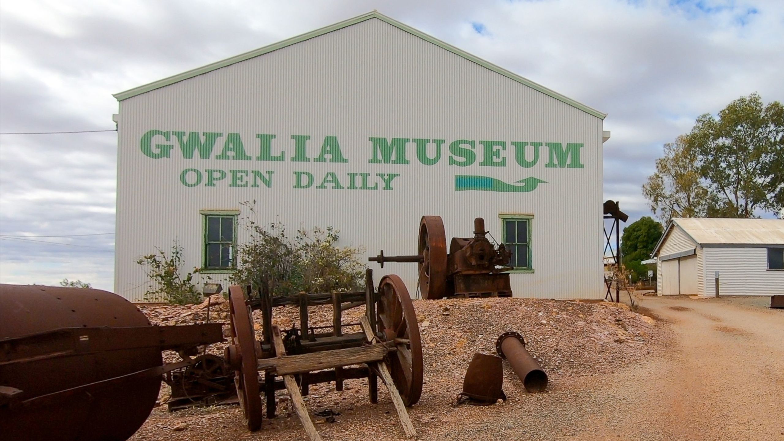 Exterior view of the Gwalia Museum shed in Western Australia, with historic mining machinery and rusted equipment on display.