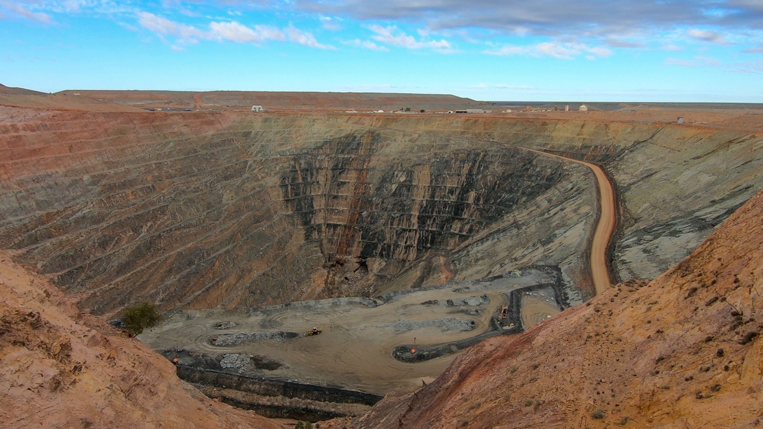 View of the Gwalia open cut gold mine in Western Australia, showing terraced mine walls descending into the earth with mining trucks in view.