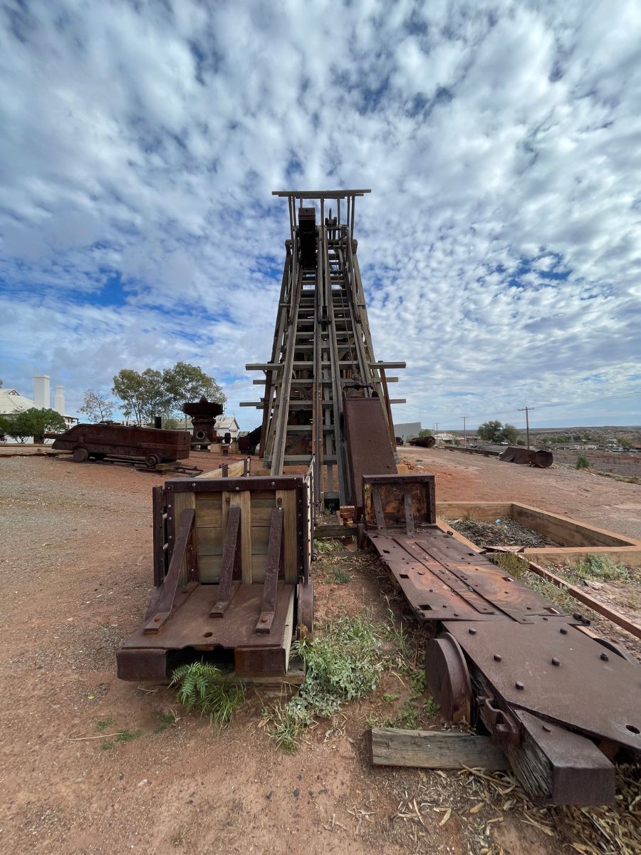 Historic timber incline head frame at the Gwalia gold mine in Western Australia, set against a backdrop of cloudy sky.